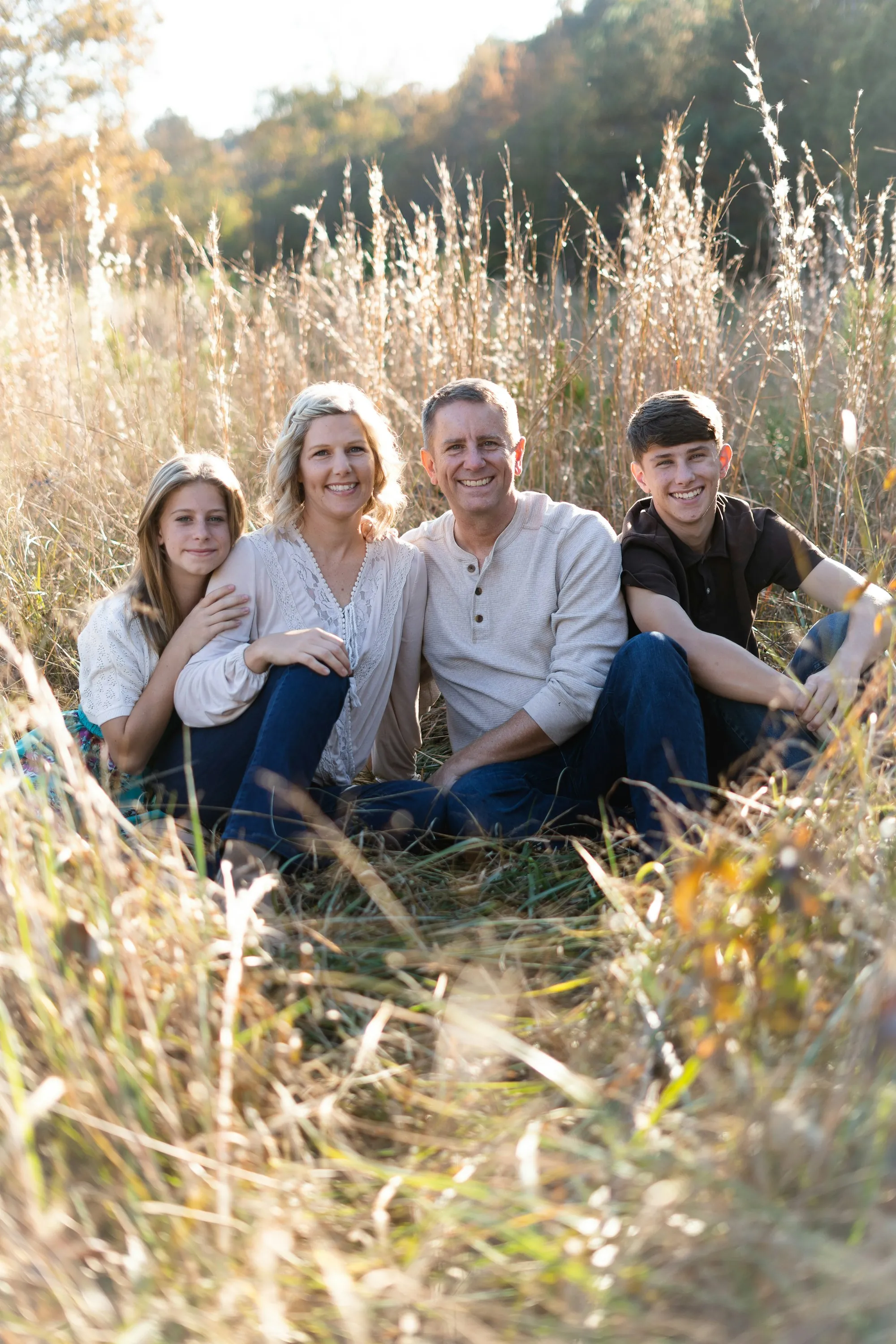 Parents and two teenagers sitting together in a meadow