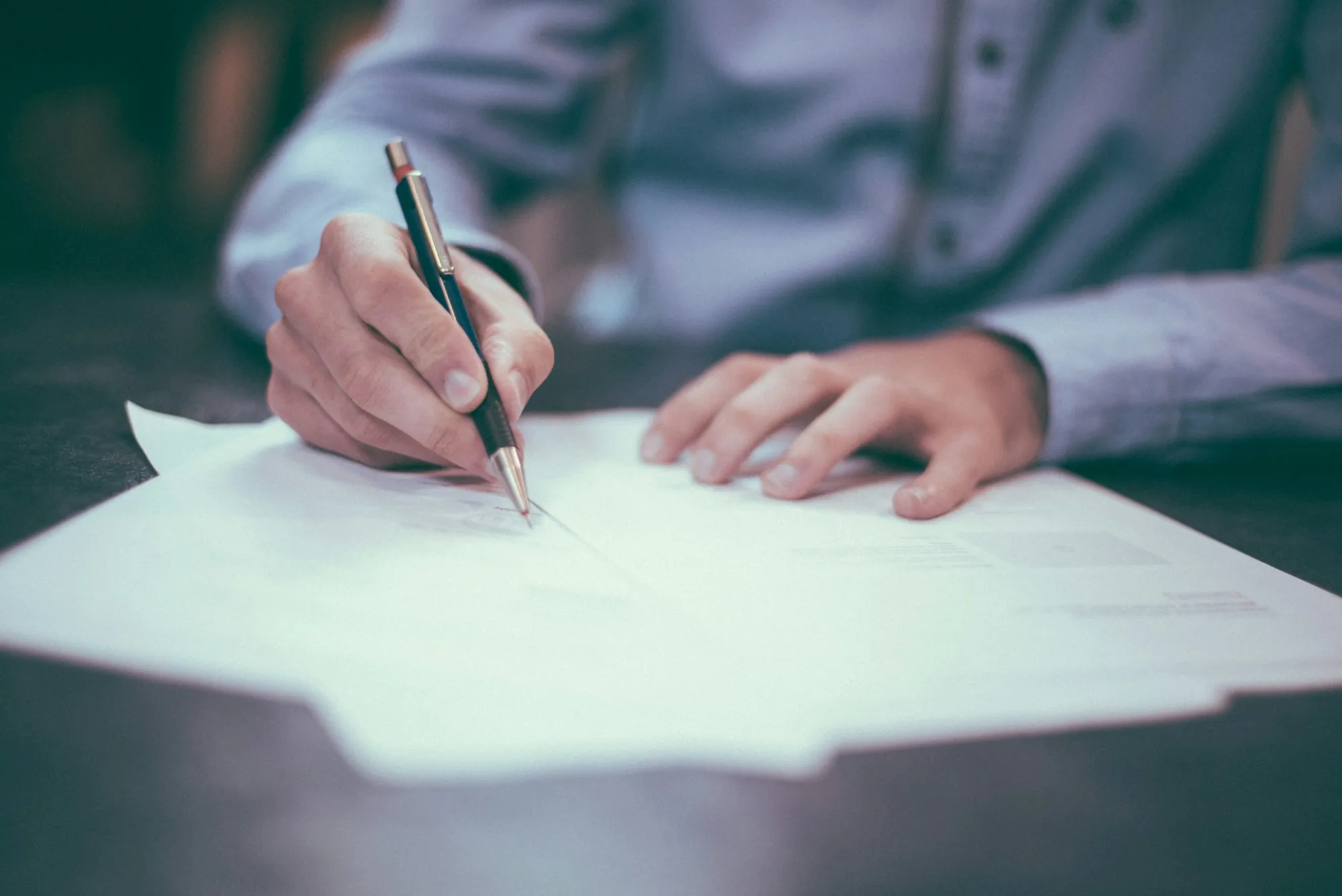 Person signing a document with a fountain pen